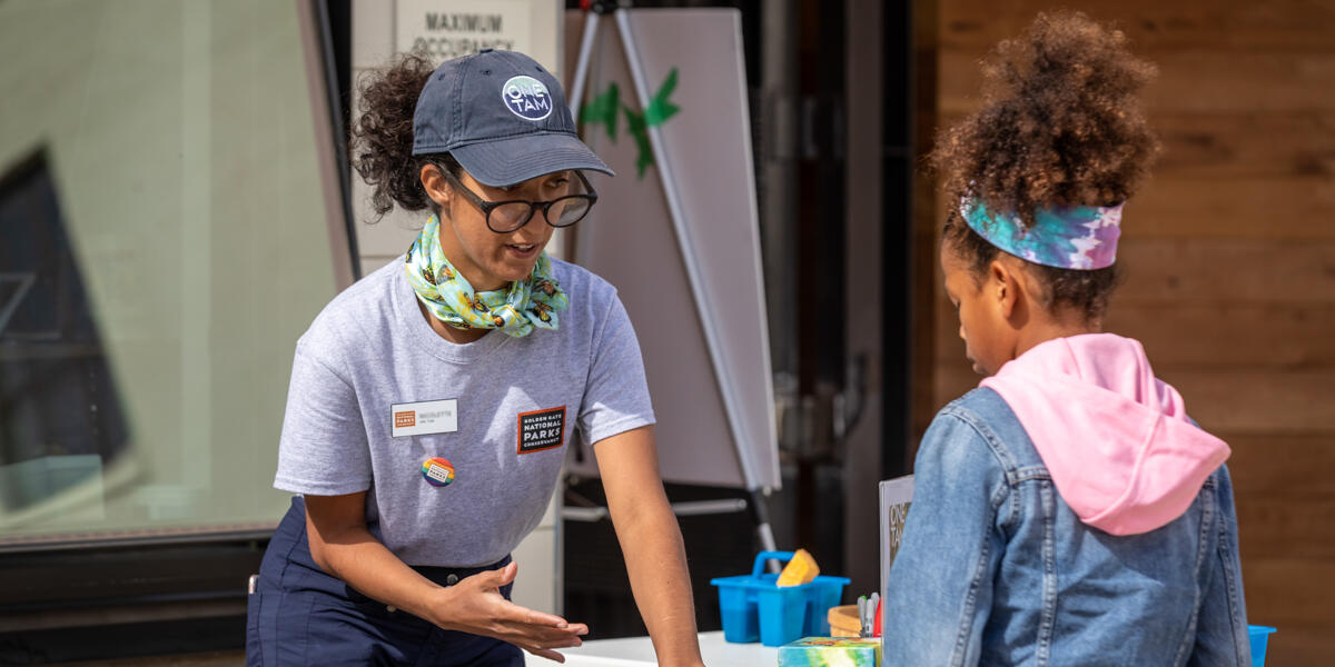 Parks Conservancy staff member talking with a young girl at a Presidio Tunnel Tops event.
