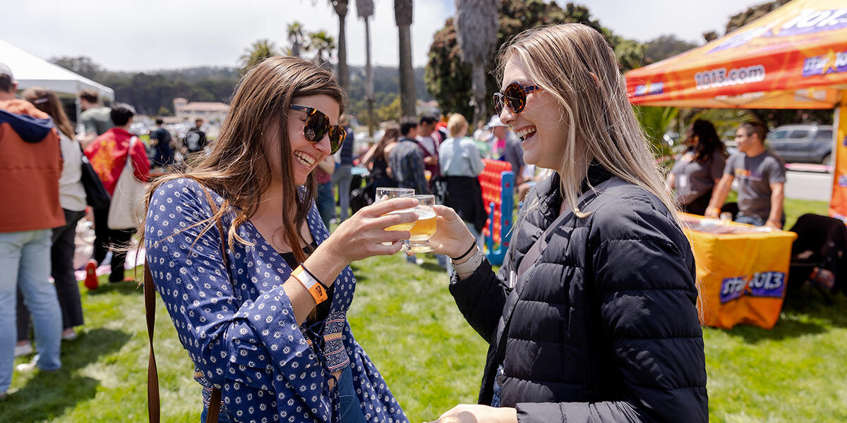 Friends cheers with souvenir beer tasting glasses at Parks4All: Brewfest, a beer festival and fundraiser, on Saturday, July 29th, 2023 in the Presidio of San Francisco.