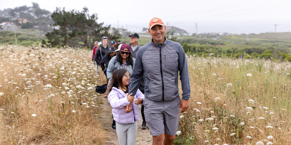 A parent and child lead a group of hikers along a trail at Rancho Corral de Tierra