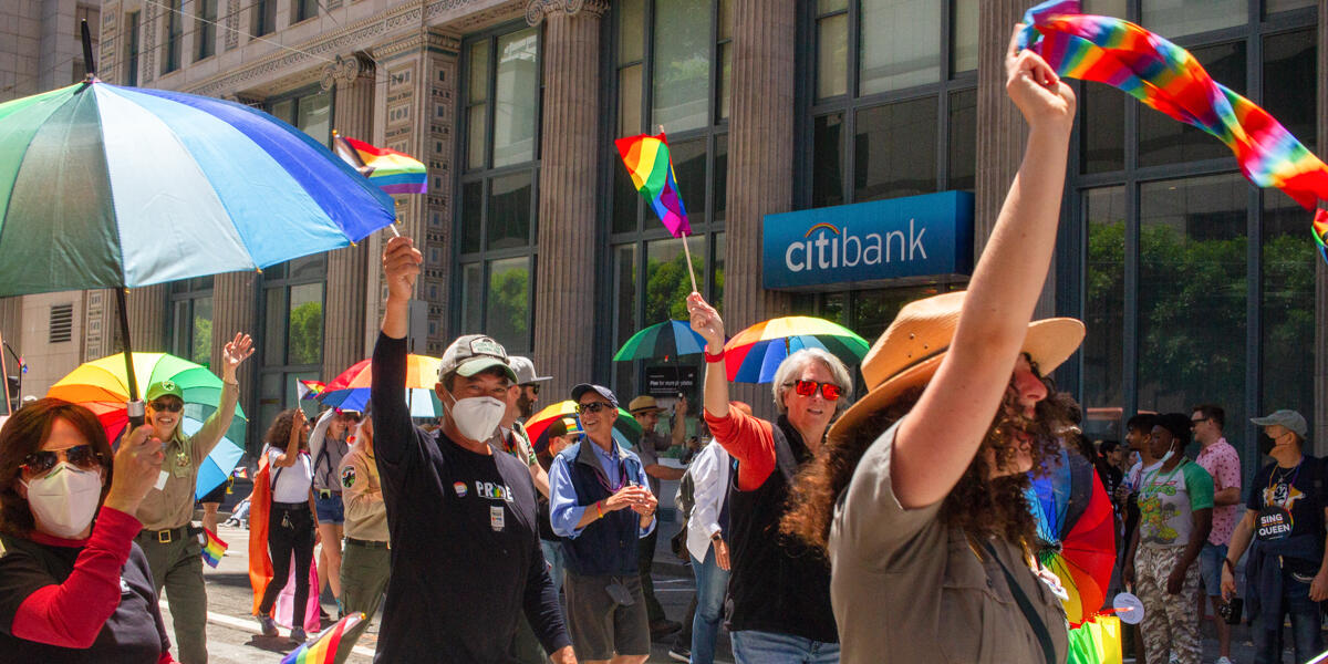 Golden Gate National Parks partners celebrate Pride, waving rainbow flags and smiling to the crowd.