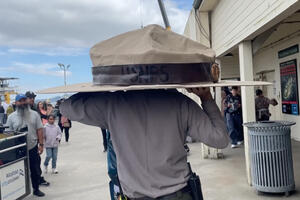 Two NPS staff members carry the Big Hat to the Alcatraz ferry. 