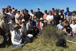 A large group of volunteers poses outside on a sunny day