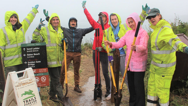 Volunteers in rain gear celebrate their hard work on the Coastal Trail.