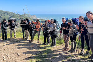 IYEL youth program participants pose before the scenic backdrop of trees and ocean on a backpacking trip in Marin
