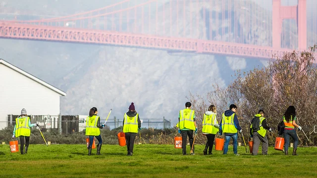 A group of volunteers in neon vests with the Golden Gate Bridge nearby