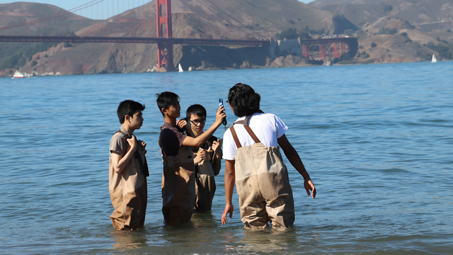 a small group of high school students learn to use environmental testing tools with an educator from the Crissy Field Center