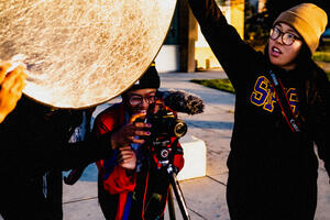 Crissy Field Center youth program participants working a photoshoot, holding a camera and light reflector.