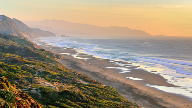 Scenic view overlooking the beach and bluffs of Fort Funston stretching out to the pacific ocean and gorgeous sunset