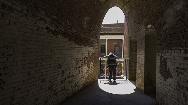 A dark hall leads to a person looking down through a sunny archway on one of Fort Points upper levels