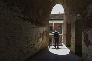 A dark hall leads to a person looking down through a sunny archway on one of Fort Points upper levels