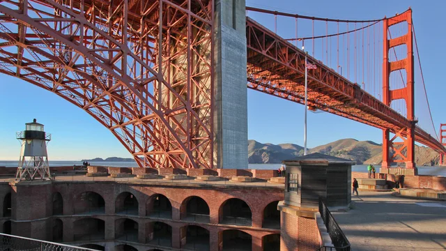 View of the Golden Gate Bridge and the top of Fort Point National Historic Site set against a blue sky