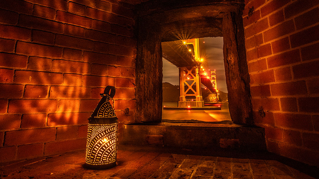 A lantern cast shadows on brick walls at Fort Point.