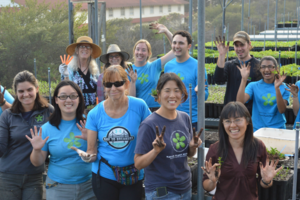 A large group smiles and holds up dirty hand while working in the nursery.