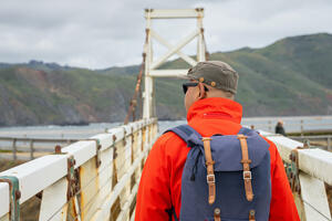 Person in red jacket with a blue backpack talking down the pathway at Point Bonita Lighthouse.