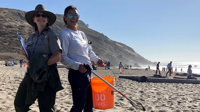 Two volunteers posing with supplies while cleaning up Muir Beach