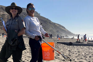 Two volunteers posing with supplies while cleaning up Muir Beach