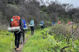 Group of youth backpacking along a trail.