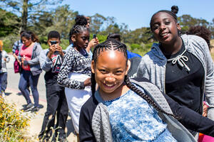 A youth group smiling as they hike through Presidio trails in San Francisco
