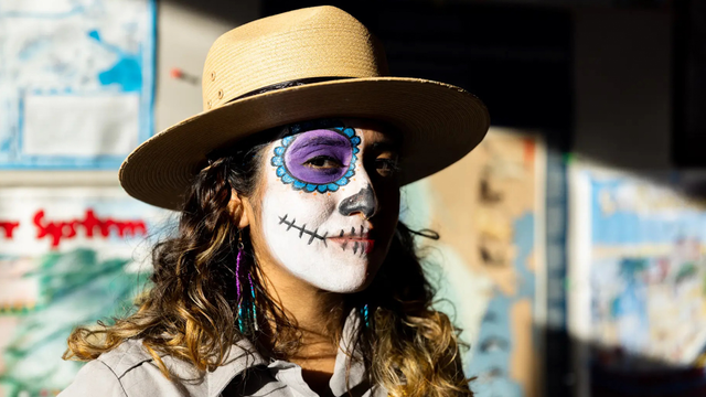A portrait of an  NPS ranger with candy skull face paint on for Dia de los Muertos.