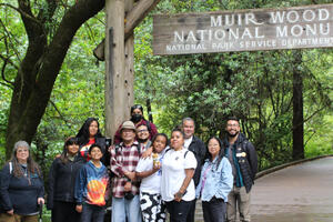 A group from the American Indian Cultural District stands together at the entrance of Muir Woods National Monument