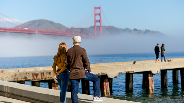 A couple stops to take in a Golden Gate Bridge view at Crissy Field East Beach