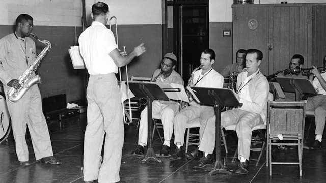A historic black-and-white photograph of a group of incarcerated musicians at Alcatraz Island playing in a prison band. 