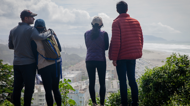 Four people stand on edge of Sutro Heights Parks looking out towards Ocean Beach and Golden Gate Park