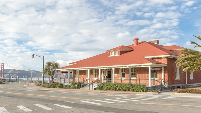 Image of the front of the Presidio Visitor Center with the Golden Gate Bridge in the backgrounr
