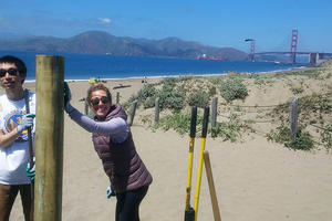 Trail Crew volunteers help install fence posts at Baker Beach.