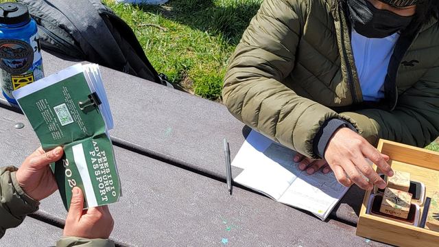 Adventure Guides sit at a park bench, stamping Presidio Adventure Passports.