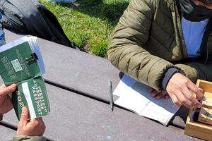 Adventure Guides sit at a park bench, stamping Presidio Adventure Passports.