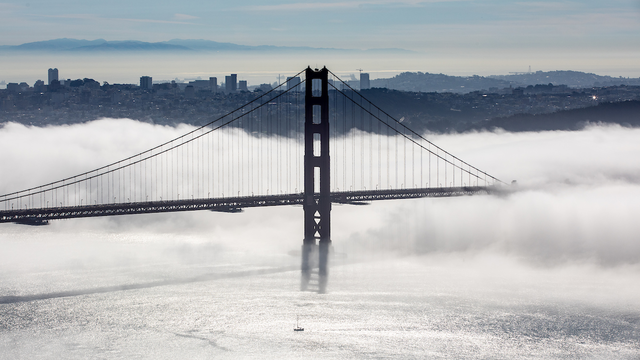 Golden Gate bridge in a layer of fog with a view of San Francisco behind it. 