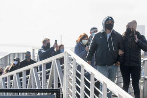 a group of masked visitors disembark from a ship onto Alcatraz