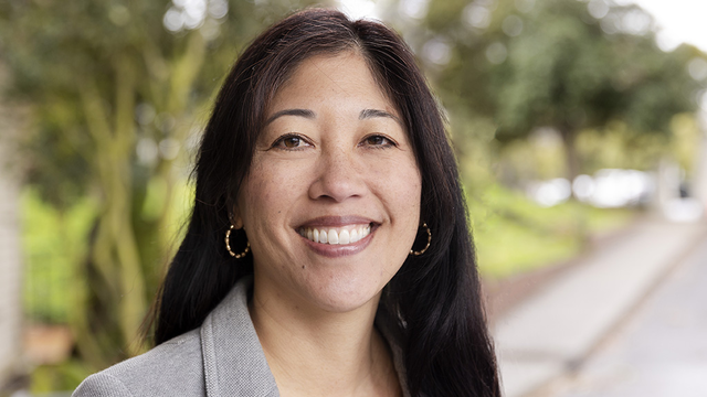 Michele Gee stands in front of a green background in the parks.
