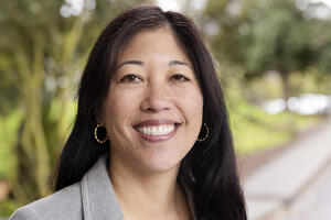Michele Gee stands in front of a green background in the parks.