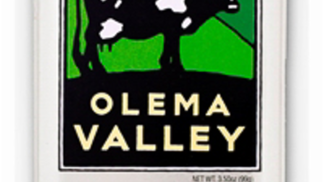 A metal tin with the image of a cow standing in a grassy hillside