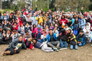A large group of cheerful teenagers excitingly cheer at Rob Hill Campground in the Presidio of San Francisco