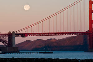 The moon rises above the bridge