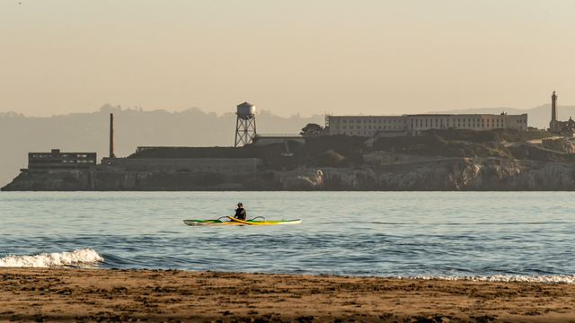 A Kayak paddles over the Golden Gate waters, viewed before Alcatraz Island from Crissy Field East Beach.