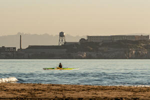 A Kayak paddles over the Golden Gate waters, viewed before Alcatraz Island from Crissy Field East Beach.