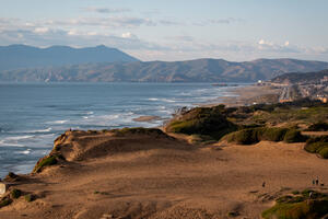 An aerial view of Fort Funston shows the ocean, beach, cliffsides, and looks on to the golden gate.