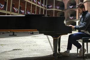 Pianist plays piano surrounded by the red-bricked Fort Point.