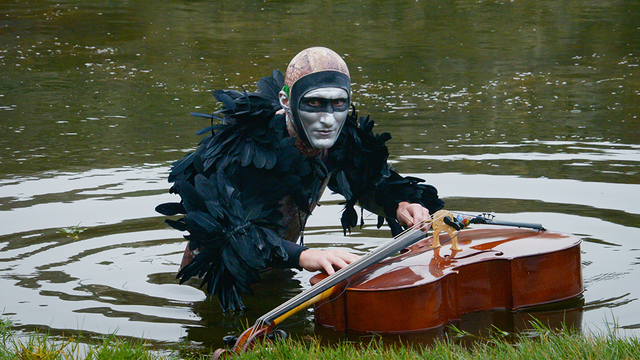 Musician Andy Meyerson wears an elaborate costume with a cello floating in Sutro Baths.