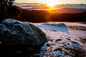 Snow on a boulder on mount tam at sunrise.