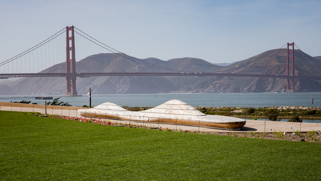 An artistically crafted bench at Presidio Tunnel Tops sits before the Golden Gate Bridge and Marin Headlands in the background.