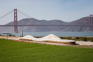 An artistically crafted bench at Presidio Tunnel Tops sits before the Golden Gate Bridge and Marin Headlands in the background.