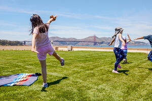 Kids stretch and play, running around the Presidio Tunnel Tops lawn.