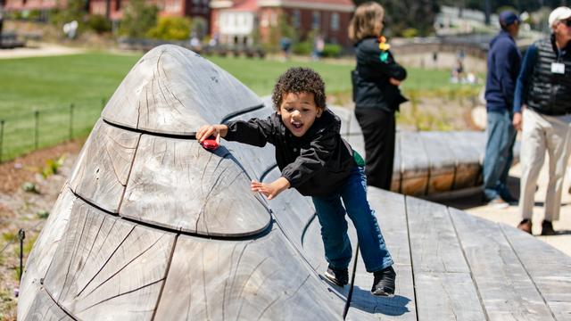 A child plays with their toy car on the contoured benches at the Presidio Tunnel Tops.