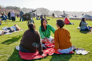 People sit and lay on blankets all about the Golden Gate Meadow at Presidio Tunnel Tops.