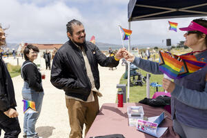 Staff hand out mini rainbow flags to park visitors.